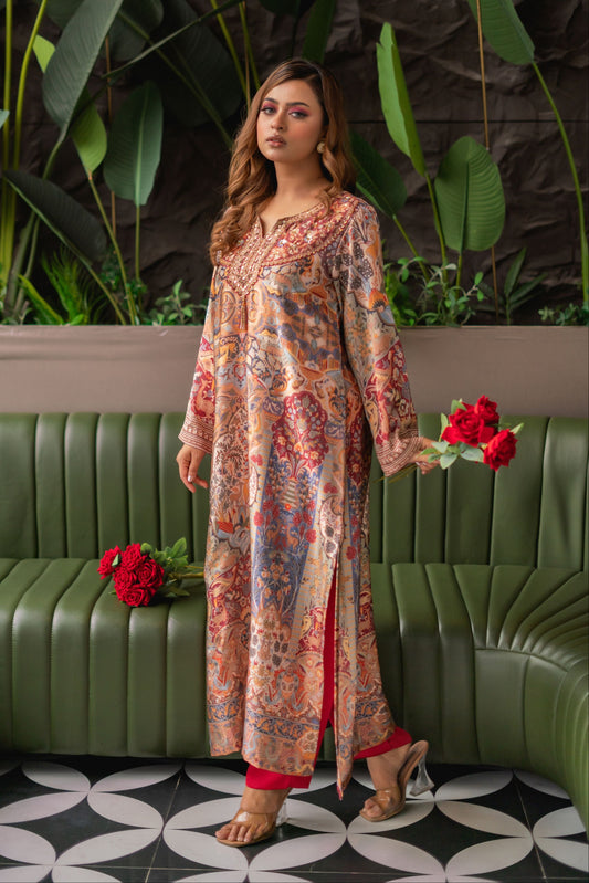 Woman in a floral dress standing in front of a green couch with red flowers.
